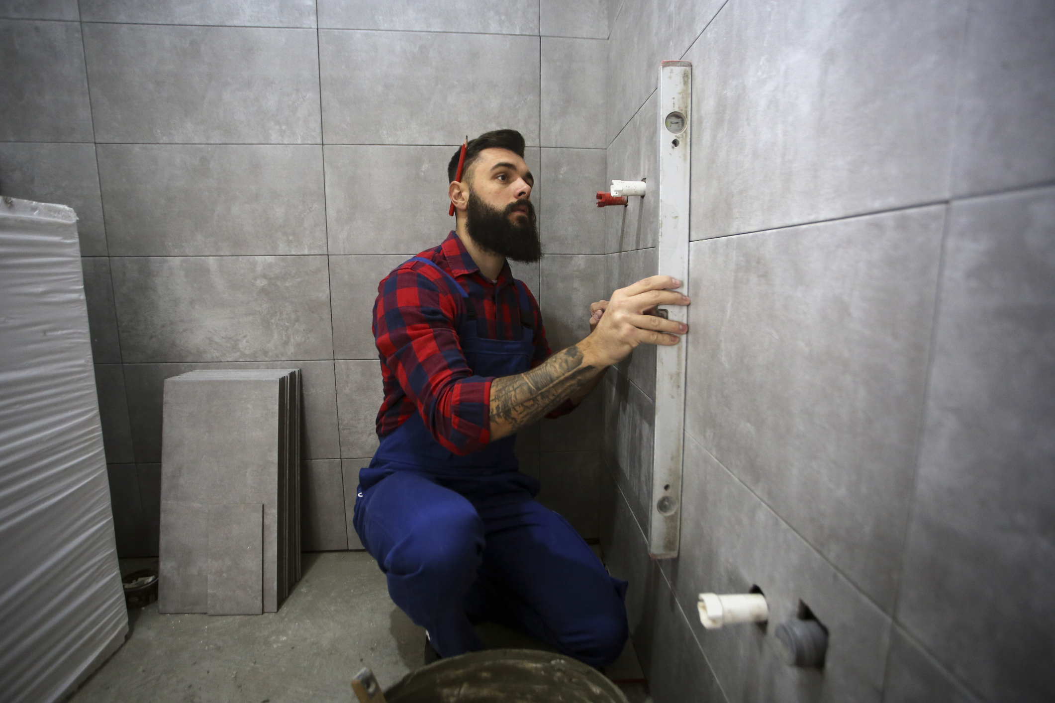 mężczyzna mierzy poziomicą ścianę w łazience